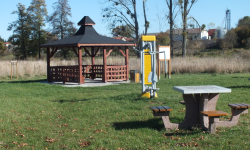 Zdjęcie przedstawia stolik z ławkami, siłownię zewnętrzną i altankę