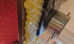 Z dzbanka nalewany jest żółty płyn do małych słowiczków stojących na stole. 