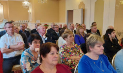 Kobiety i mężczyźni siedzą  na krzesłach d dużej sali. Konferencja LGD. Hrubieszów.