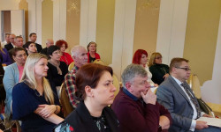 Konferencja LGD. Hrubieszów. Kobiety i mężczyźni siedzą  na krzesłach d dużej sali. 