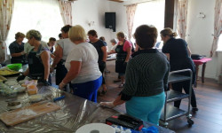 w sali grupa kobiet przy stole na którym są produkty spożywcze  