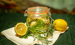 Na stole w słoiczku znajdują się marynowane śledzie z rozmarynem