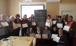 Grupa 15 kobiet stoi  pozując do zdjęcia. W ręku trzymają dyplomy