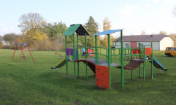 Zdjęcie placu zabaw w Peresołowicach, huśtawka, zjeżdżalnia i ścianka wspinaczkowa.