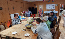 w dużej sali przy stole kilka kobiet je posiłek 