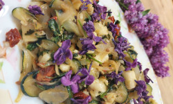 na kolorowym owalnym talerzu potrawa z cukinii i  białego sera udekorowana kwiatem bzu lilaka 