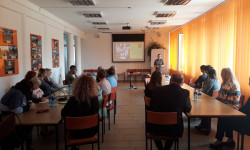 grupa ludzi przy stole i osoba prowadząca rozmawiają