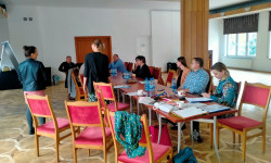 grupa uczestników spotkania siedzących przy stole prowadzą dyskusję