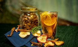 Na stole znajdują się suszone jabłka i pomarańcze oraz kompot